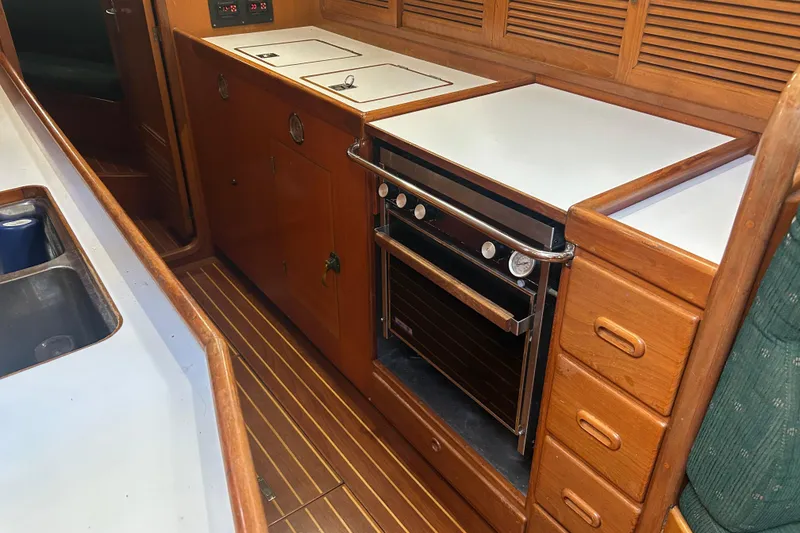 Slide: The Image of Interior of 1995 Tayana 48 yacht featuring a wooden galley with stove and storage. - 28