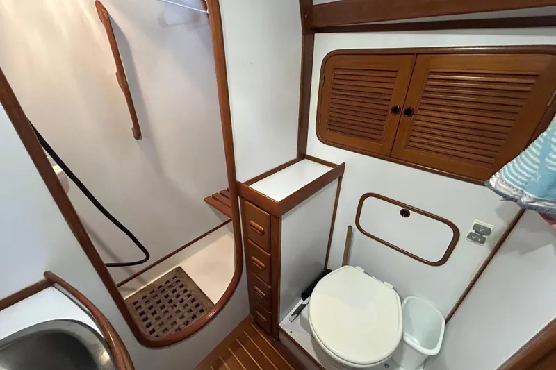Slide: The Image of Bathroom interior of a 1995 Tayana 48 yacht, featuring wooden cabinetry and a shower area. - 32