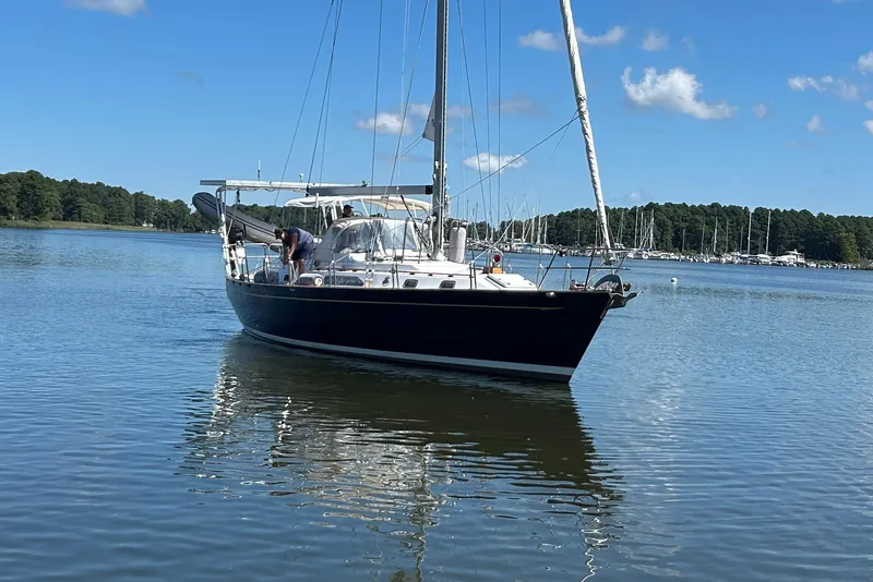 Slide: The Image of Sailboat on calm water, 1995 Tayana 48, with clear blue sky and distant marina. - 37
