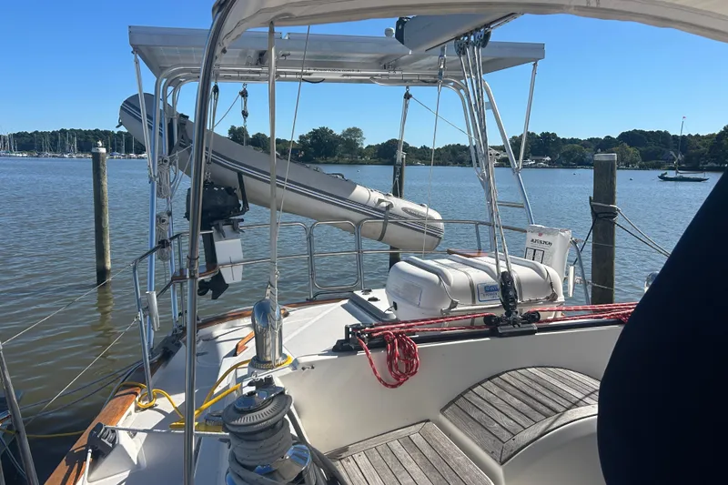 Slide: The Image of Sailboat deck view of 1995 Tayana 48, featuring lifeboat and calm marina backdrop. - 42