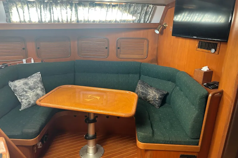 Slide: The Image of Cozy interior of 1995 Tayana 48 yacht with green seating and wooden table. - 9