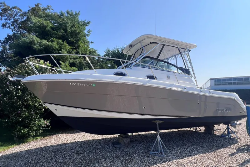 Slide: The Image of 2007 Robalo R305 Walkaround boat on stands, surrounded by greenery, under clear blue sky. - 24