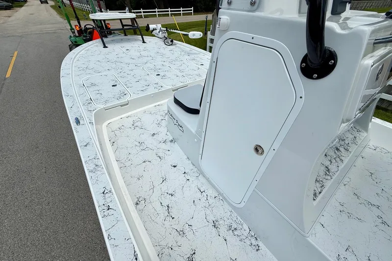 Slide: The Image of 2024 Shallow Sport 25 X3 boat with marble-patterned deck, parked on a roadside. - 11