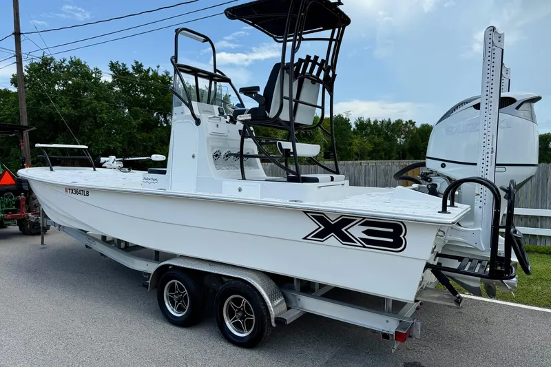 Slide: The Image of 2024 Shallow Sport 25 X3 boat on trailer, featuring elevated seating and Suzuki outboard motor. - 2
