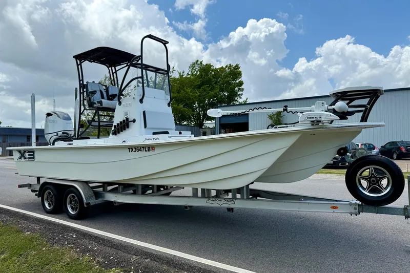 Slide: The Image of 2024 Shallow Sport 25 X3 boat on trailer, parked outdoors under cloudy sky. - 5