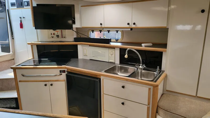 Slide: The Image of 1994 Maxum 3200 SCR boat interior with kitchenette, sink, stove, and TV. - 20