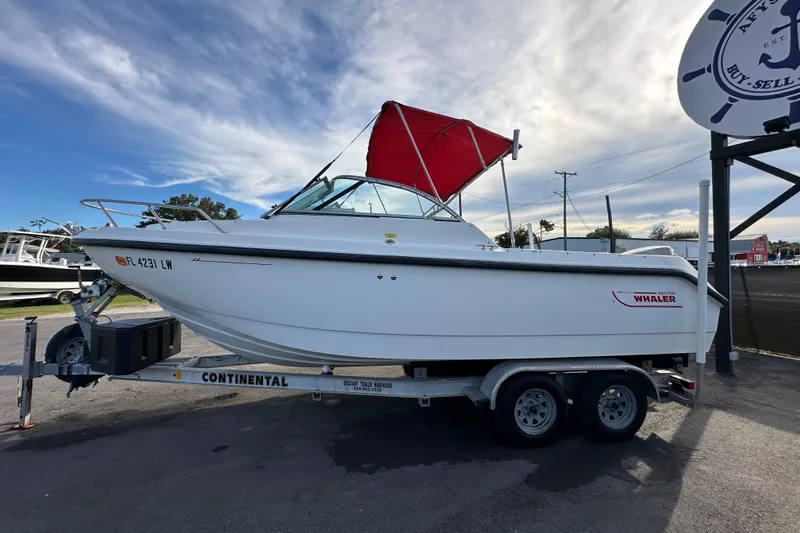 Slide: The Image of 2002 Boston Whaler 210 Ventura boat on trailer with red canopy, parked outdoors. - 7
