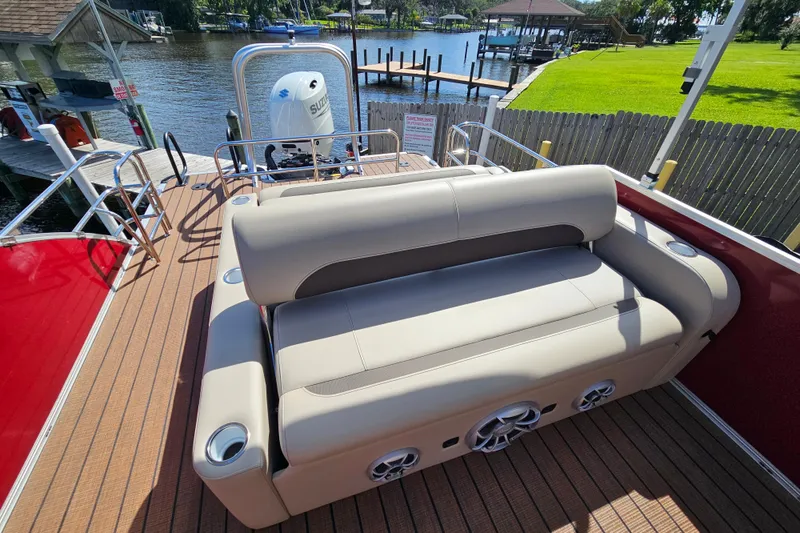 Slide: The Image of 2025 Bentley Pontoons Legacy 243 Swingback with luxurious seating, docked by a scenic waterfront. - 26