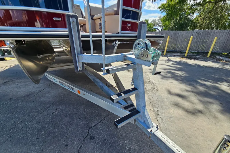 Slide: The Image of 2025 Bentley Pontoons Legacy 243 Swingback on trailer, showcasing pontoon and winch system. - 31
