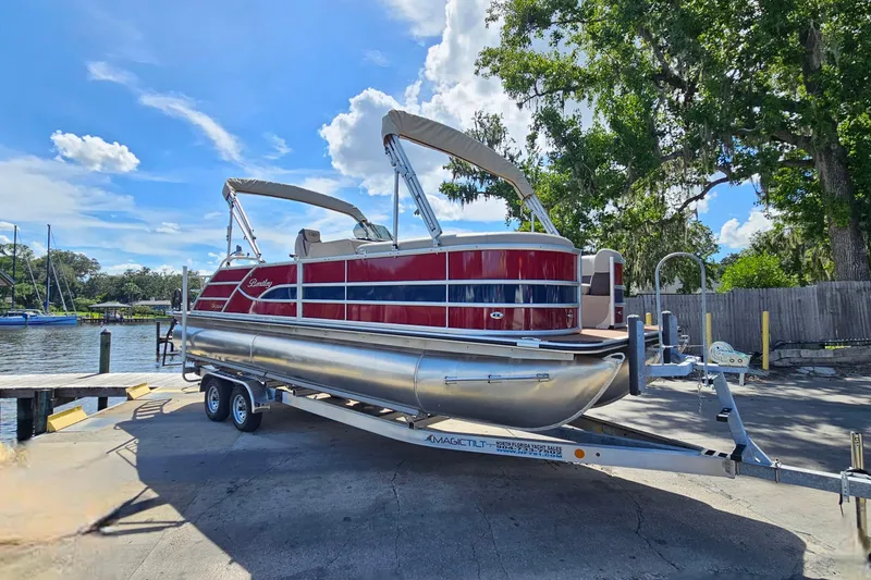 Slide: The Image of 2025 Bentley Pontoons Legacy 243 Swingback on trailer by a scenic waterfront. - 7