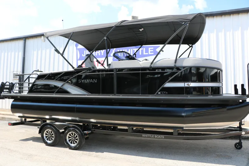The Image of 2025 Sylvan L3 CLZ DH pontoon boat on trailer, black exterior, parked outdoors. - 0