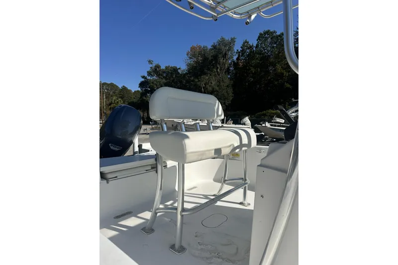 Slide: The Image of 2012 Sportsman Masters 227 Bay Boat interior with seating and console, under clear blue sky. - 12