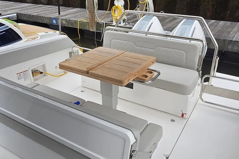 Slide: The Image of 2025 Schaefer V33 boat interior with wooden table, cushioned seating, and dual outboard engines. - 3