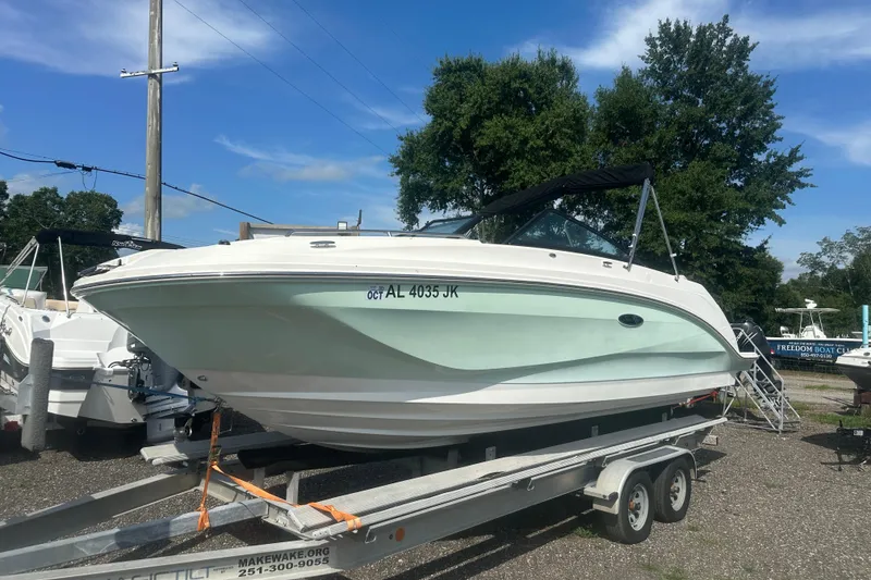 The Image of 2023 Sea Ray SDX 250 Outboard boat on trailer, parked outdoors under clear sky. - 1