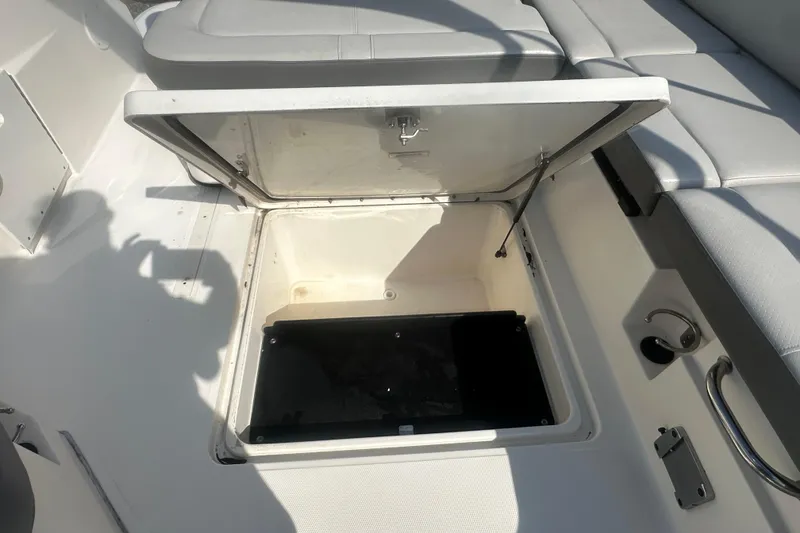 Slide: The Image of Open storage compartment on 2023 Sea Ray SDX 250 Outboard boat, featuring cushioned seating. - 23