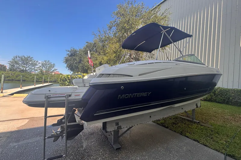 Slide: The Image of 2010 Monterey 254FS boat with canopy, white interior, and steering console, docked outdoors. - 7