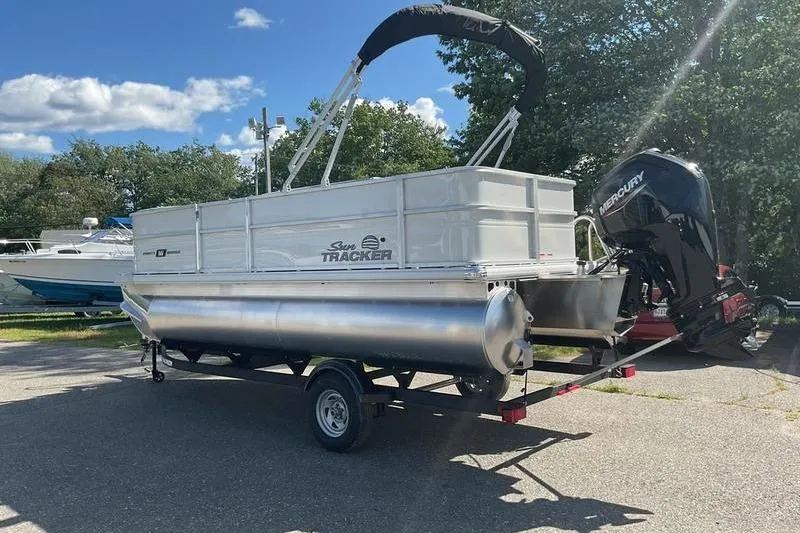 Slide: The Image of 2026 Sun Tracker PB 18 DLX pontoon boat on trailer, parked outdoors. - 10