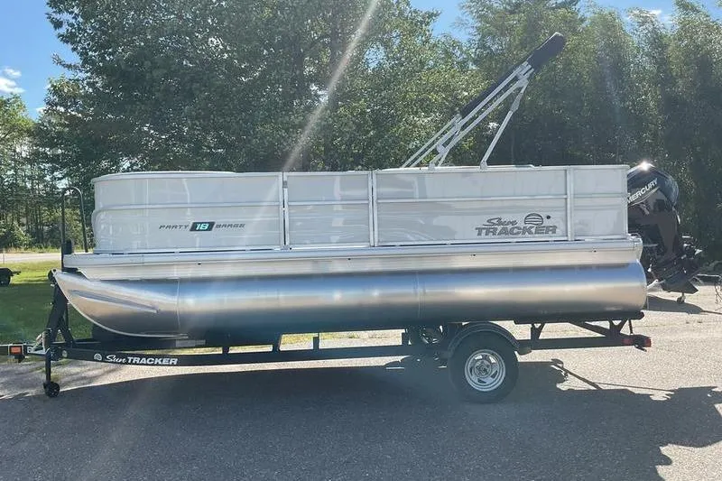 Slide: The Image of 2026 Sun Tracker PB 18 DLX pontoon boat on trailer, parked outdoors. - 4