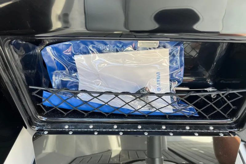 Slide: The Image of 2024 Yamaha Boats 222SE storage compartment with netting and manual. - 10