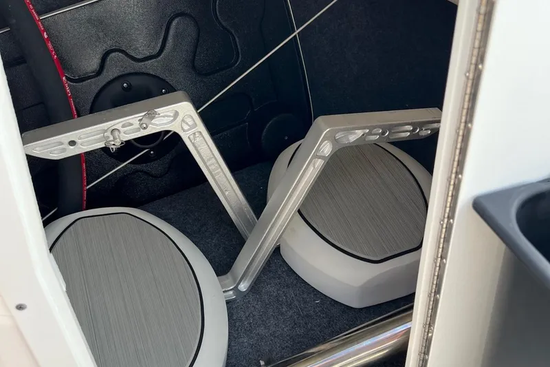 Slide: The Image of 2024 Yamaha Boats 222SE interior storage compartment with foldable seats and metal brackets. - 12