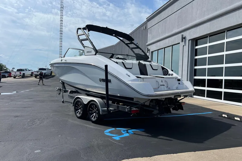 Slide: The Image of 2024 Yamaha Boats 222SE on trailer outside a modern building. - 2