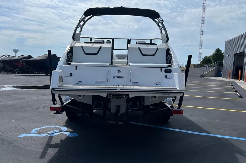 Slide: The Image of 2024 Yamaha Boats 222SE, rear view, parked in a lot near a building. - 3