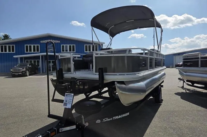 Slide: The Image of 2026 Sun Tracker BB 18 DLX pontoon boat on trailer outside showroom. - 4