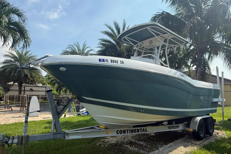 Slide: The Image of 2020 Striper 220 Center Console boat on trailer, surrounded by palm trees. - 0