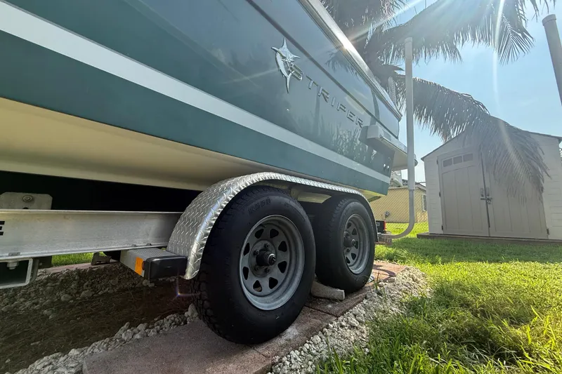 Slide: The Image of 2020 Striper 220 Center Console boat on trailer, parked near palm trees and shed. - 2