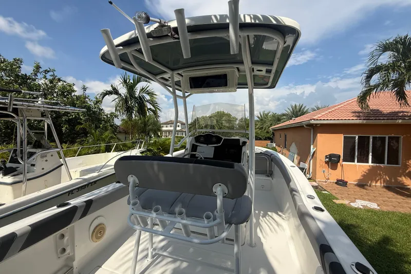 Slide: The Image of 2020 Striper 220 Center Console boat with T-top, parked near a house, surrounded by palm trees. - 22