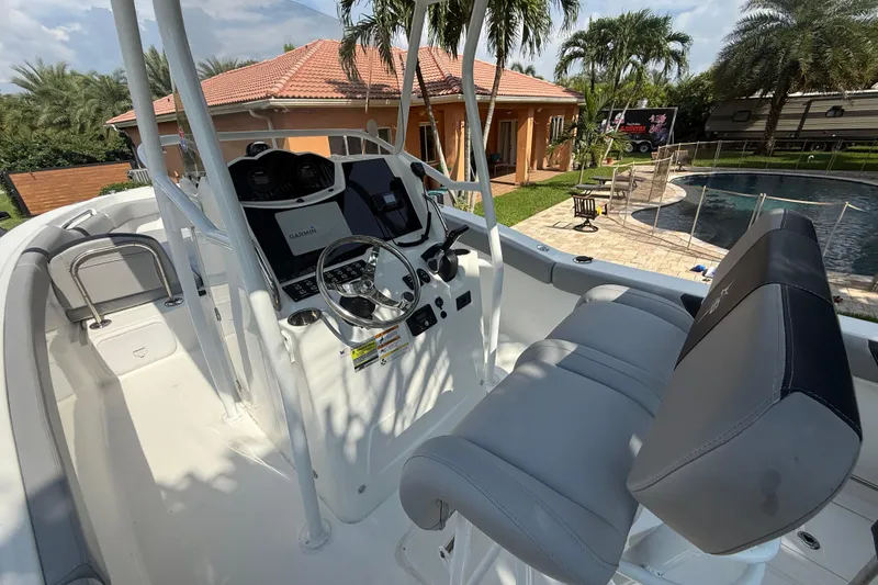Slide: The Image of 2020 Striper 220 Center Console boat with modern helm and seating, near a poolside patio. - 30