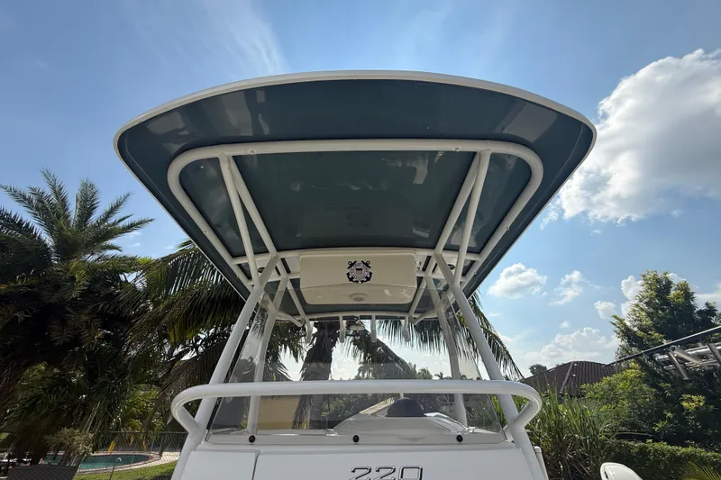 Slide: The Image of 2020 Striper 220 Center Console boat with T-top, surrounded by palm trees and blue sky. - 48
