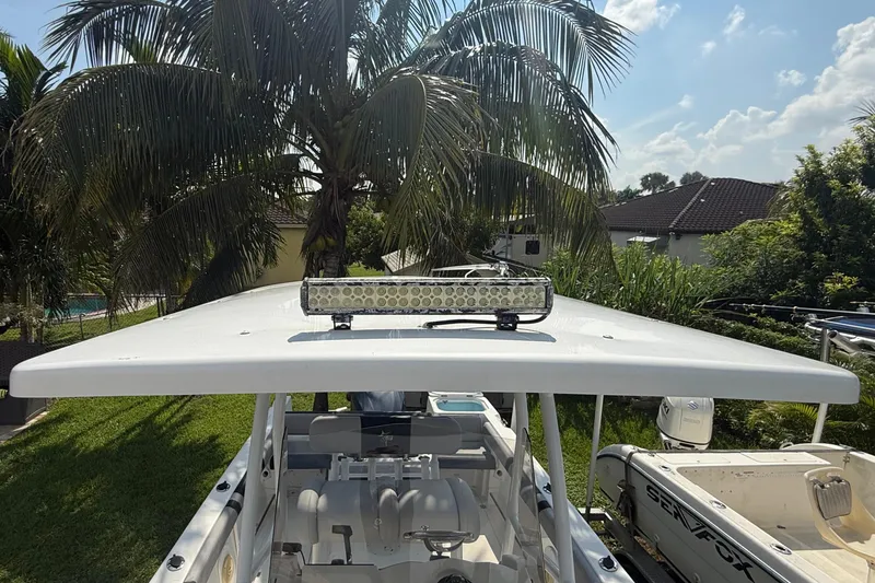 Slide: The Image of 2020 Striper 220 Center Console boat with T-top and light bar, under palm trees. - 49