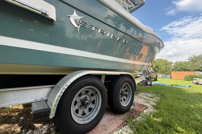 Slide: The Image of 2020 Striper 220 Center Console boat on trailer, parked on grass under blue sky. - 6