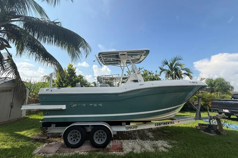 Slide: The Image of 2020 Striper 220 Center Console boat on trailer, surrounded by tropical palm trees. - 7