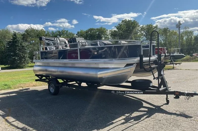 Slide: The Image of 2026 Sun Tracker BB 18 DLX pontoon boat on trailer, parked outdoors under blue sky. - 9