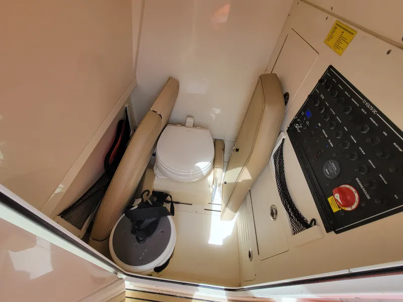 Slide: The Image of Interior of 2018 Scout 235XSF boat featuring a compact marine toilet and control panel. - 6