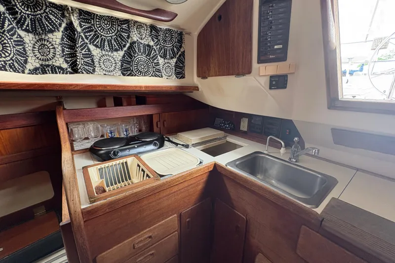 Slide: The Image of 1981 Sabre 31 yacht interior kitchen with sink, stove, and wooden cabinetry. - 127