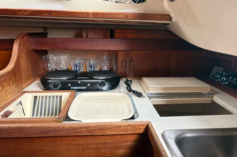 Slide: The Image of 1981 Sabre 31 yacht galley with stove, sink, and wooden cabinetry. - 128