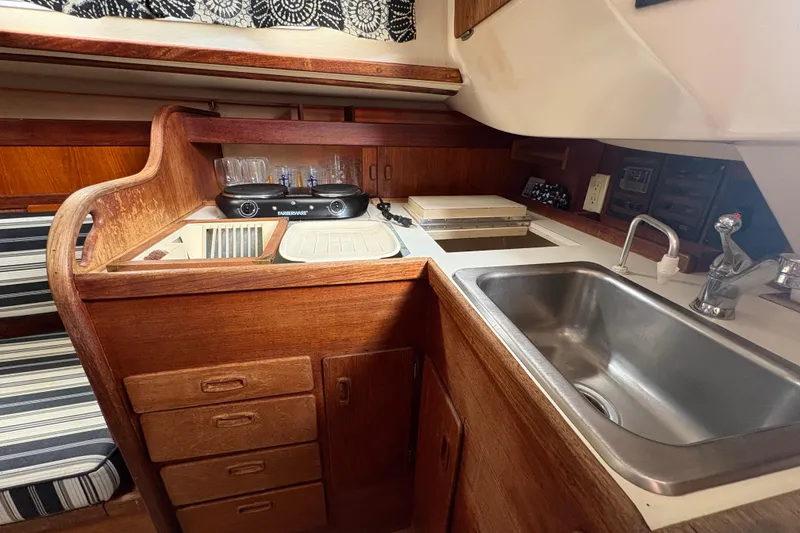 Slide: The Image of 1981 Sabre 31 yacht interior kitchen with wooden cabinetry and stainless steel sink. - 129