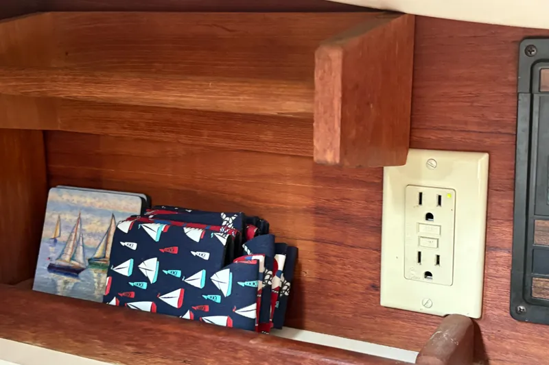 Slide: The Image of Wooden shelf with nautical-themed coasters and napkins, electrical outlet, Sabre 31, 1981. - 133