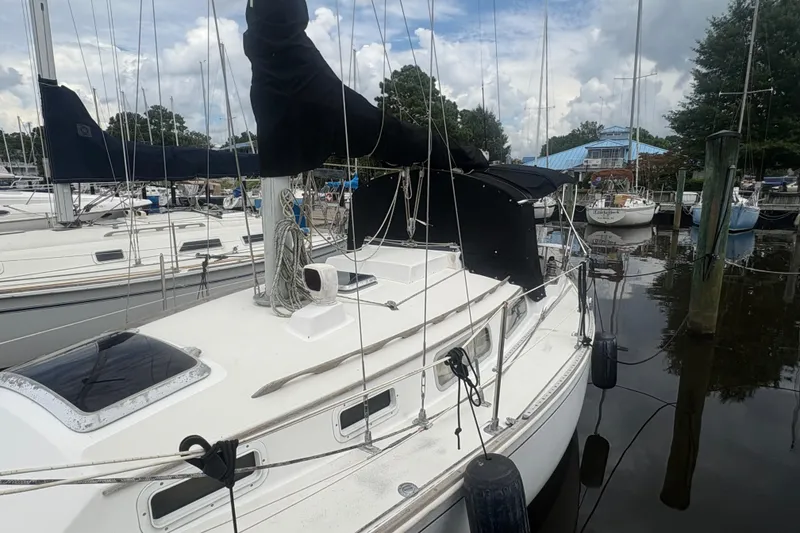 Slide: The Image of 1981 Sabre 31 sailboat docked at marina, featuring white deck and black sail cover. - 35