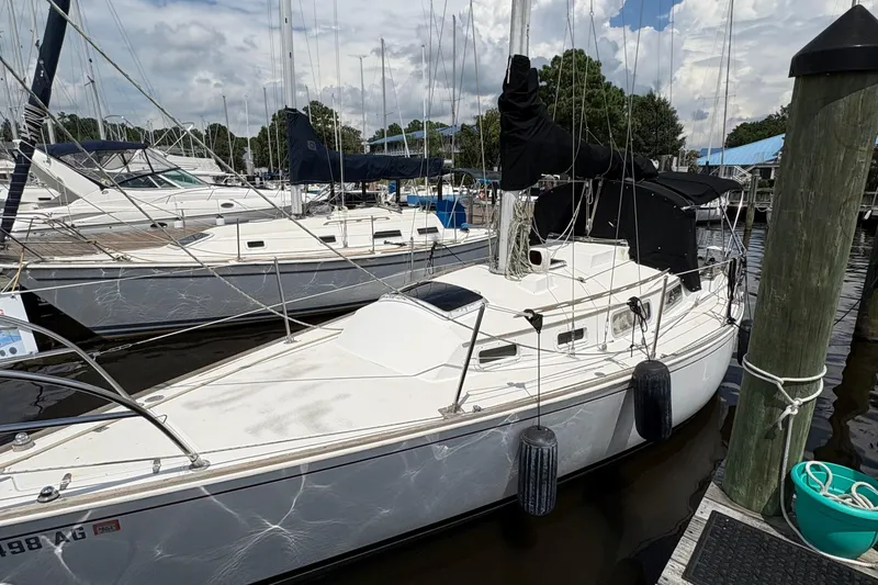 Slide: The Image of 1981 Sabre 31 sailboat docked at marina, surrounded by other boats under a cloudy sky. - 4