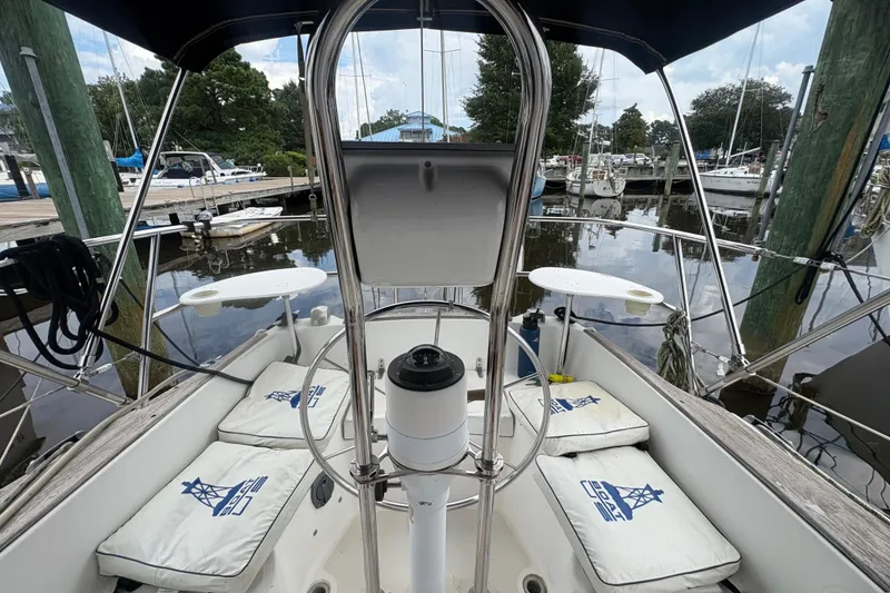 Slide: The Image of Cockpit of 1981 Sabre 31 sailboat docked at marina, featuring cushioned seating and steering wheel. - 46