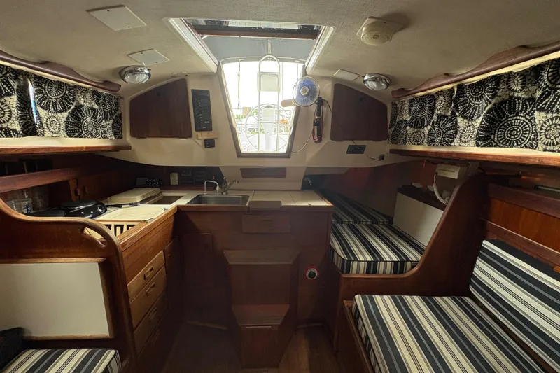 Slide: The Image of 1981 Sabre 31 yacht interior with wood finish, striped cushions, and patterned curtains. - 78
