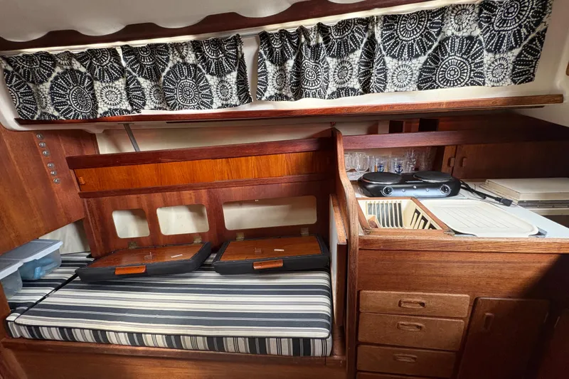 Slide: The Image of 1981 Sabre 31 yacht interior with striped seating, wooden cabinetry, and patterned curtains. - 92