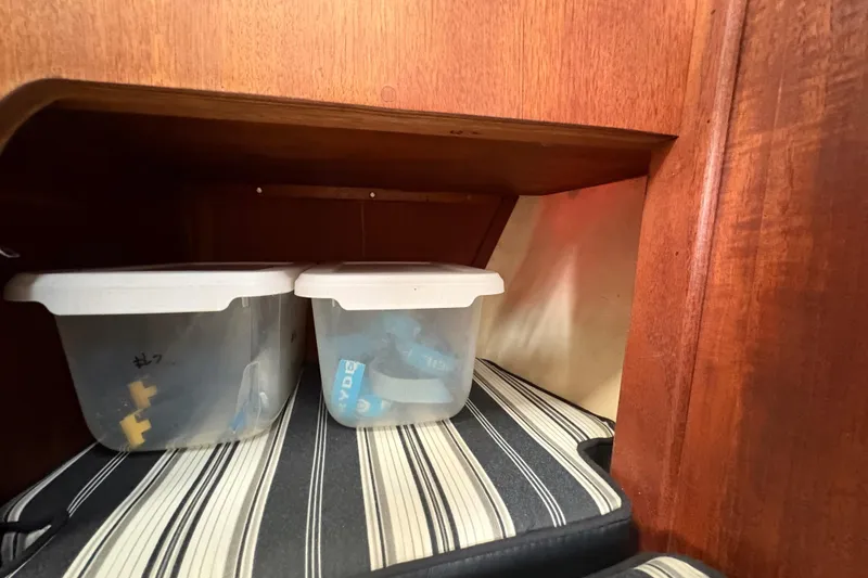 Slide: The Image of Storage area in 1981 Sabre 31 sailboat with plastic containers and striped cushion. - 99