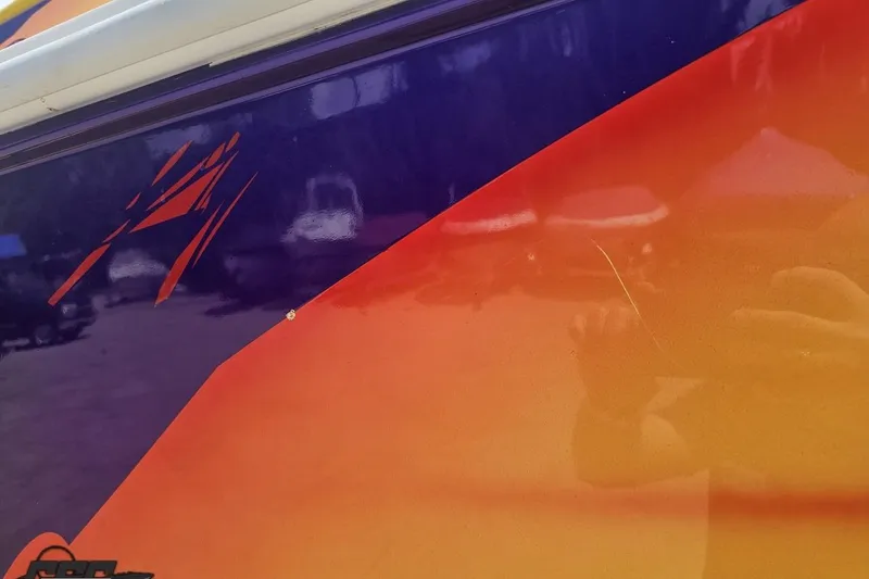 Slide: The Image of Close-up of 2003 Sonic USA 31SS boat with vibrant orange and blue design. - 11