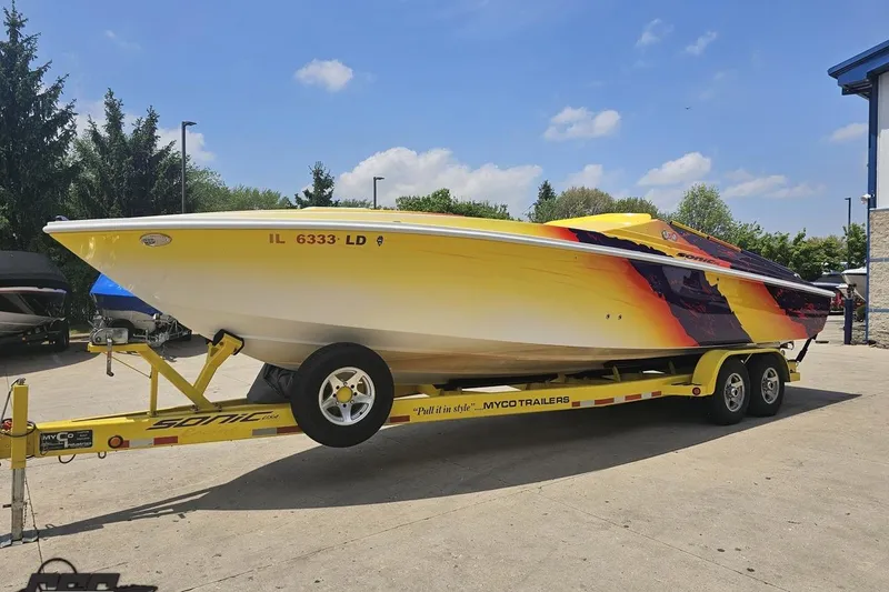 Slide: The Image of 2003 Sonic USA 31SS speedboat on trailer, vibrant yellow and red design, parked outdoors. - 15