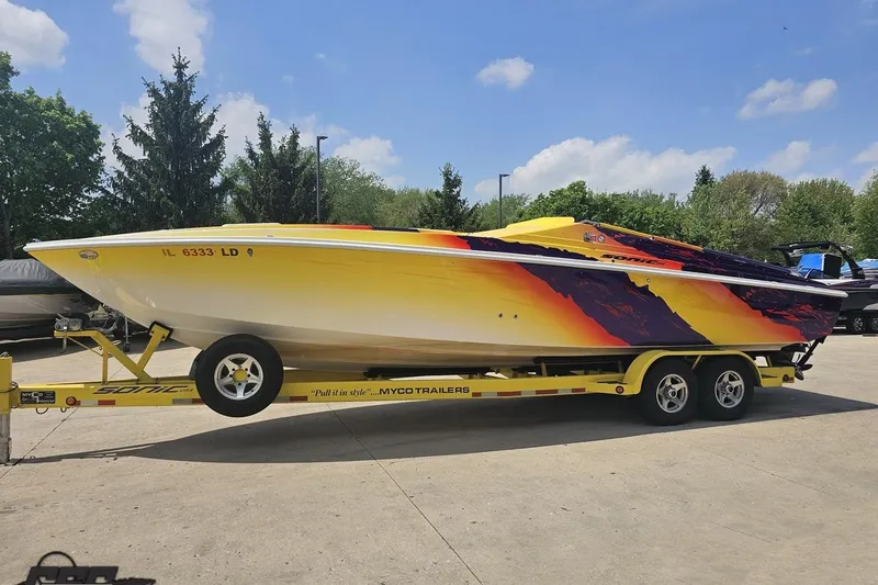 Slide: The Image of 2003 Sonic USA 31SS speedboat with vibrant yellow and red design on a trailer. - 16